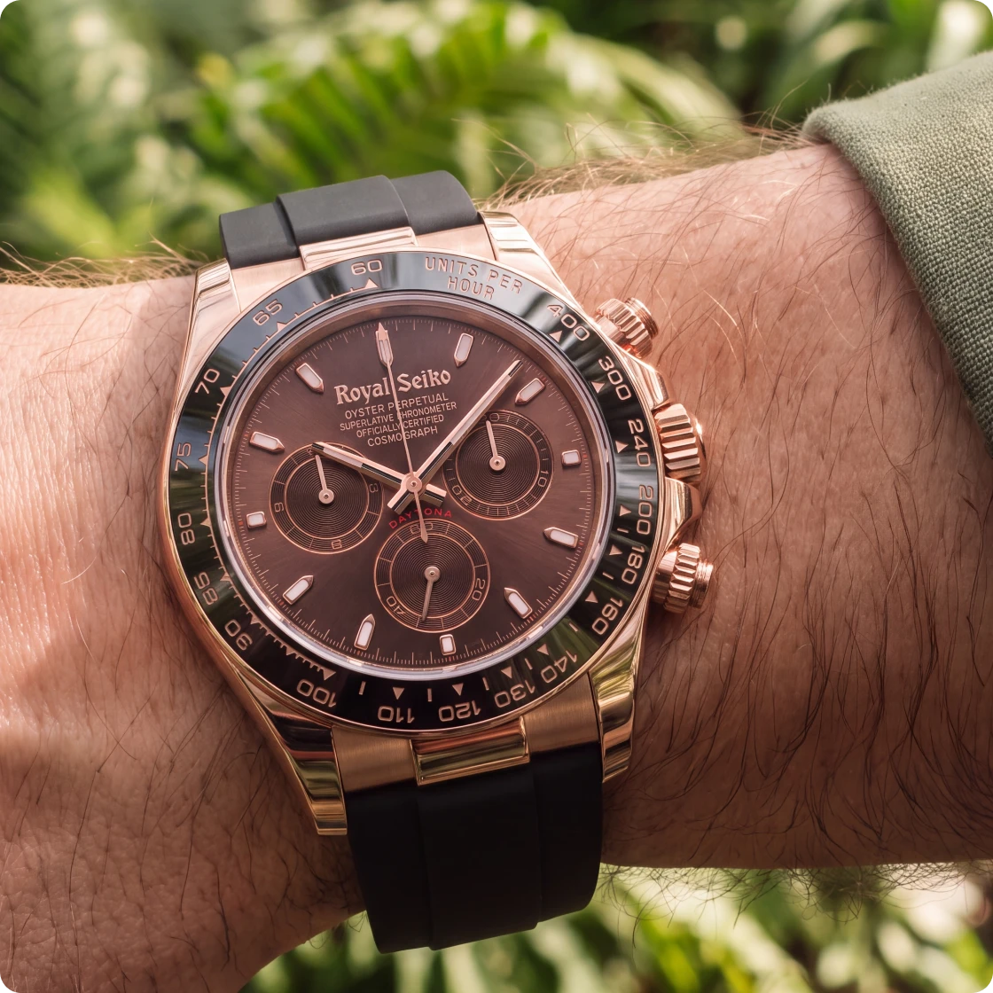 A rose gold chronograph on a rubber strap, worn on the wrist